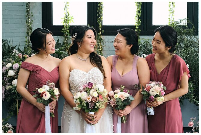 Bride and bridesmaids holding bouquets, smiling together.