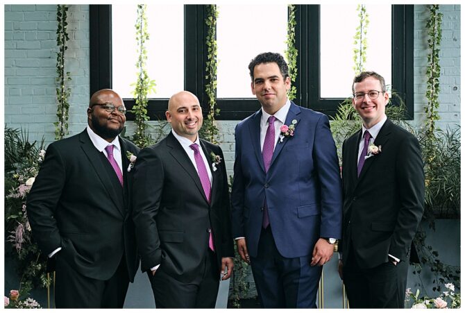 Four men in suits with floral boutonnieres.