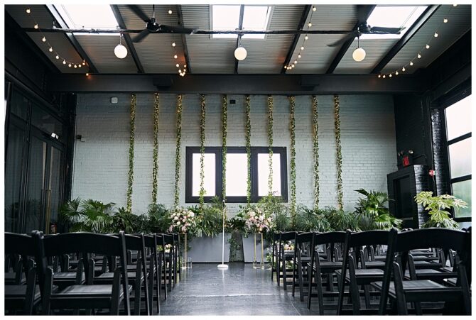 Indoor wedding ceremony setup with chairs and plants.