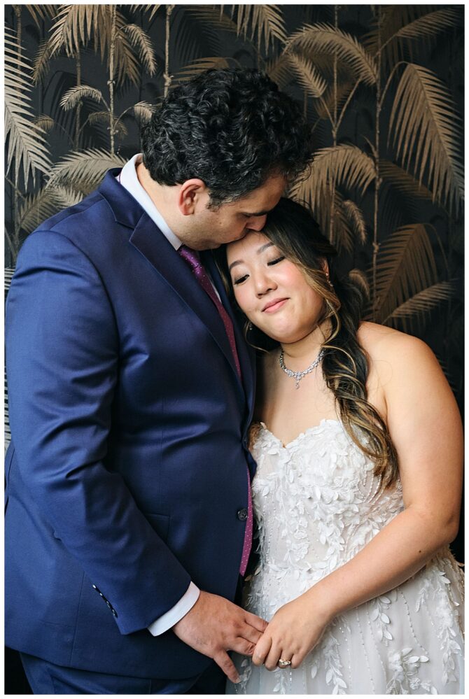 Couple embracing in wedding attire, tropical wallpaper background.