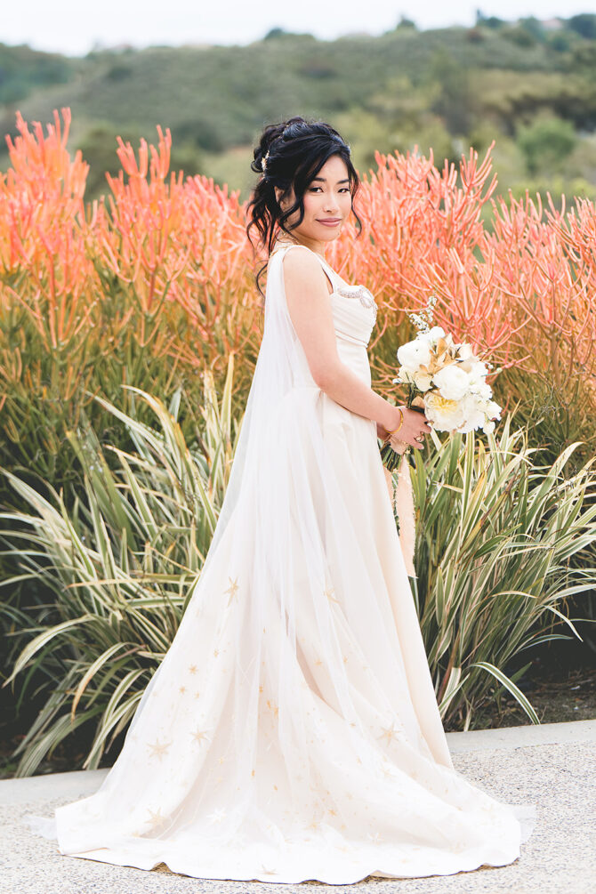 Bride in elegant dress with flower bouquet outdoors.