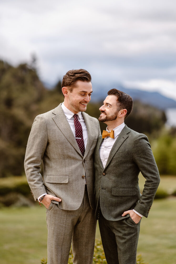 Two men smiling in elegant suits outdoors.