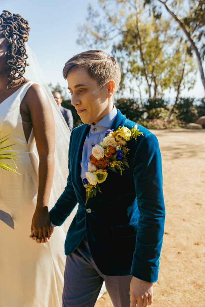 Wedding couple holding hands outdoors.