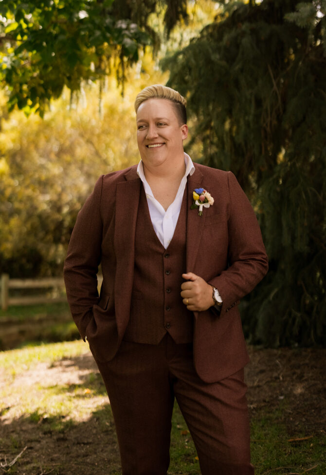 Person in brown suit smiling outdoors