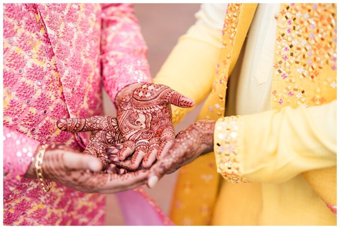 Henna designs on hands in traditional colorful attire.