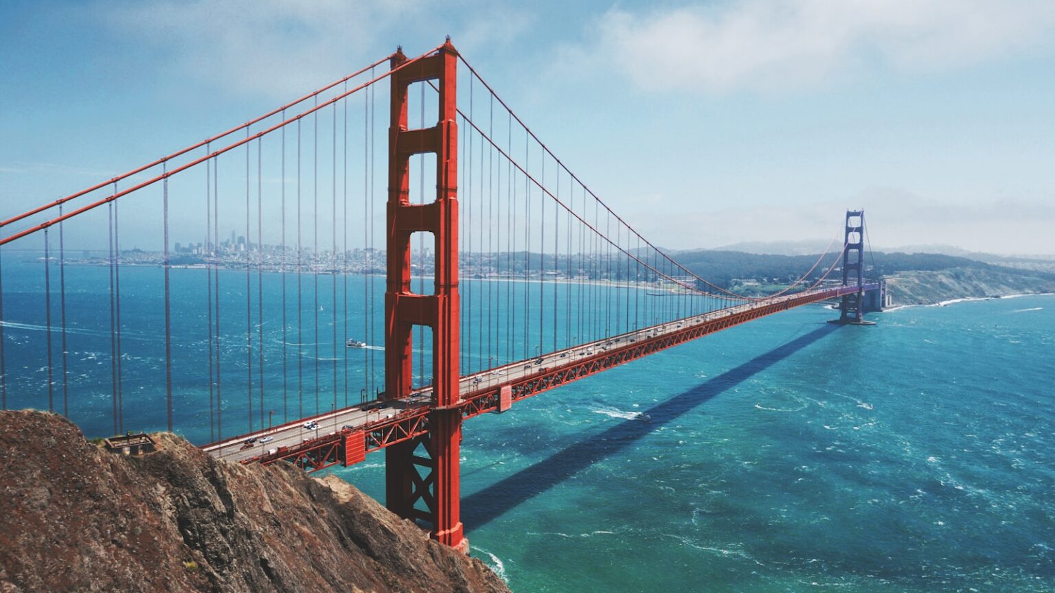 Golden Gate Bridge over blue water, clear skies.