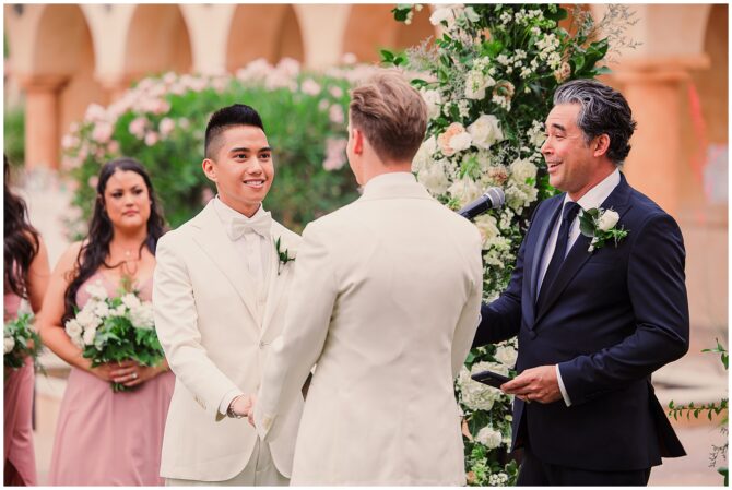 Wedding ceremony with two grooms and officiant.