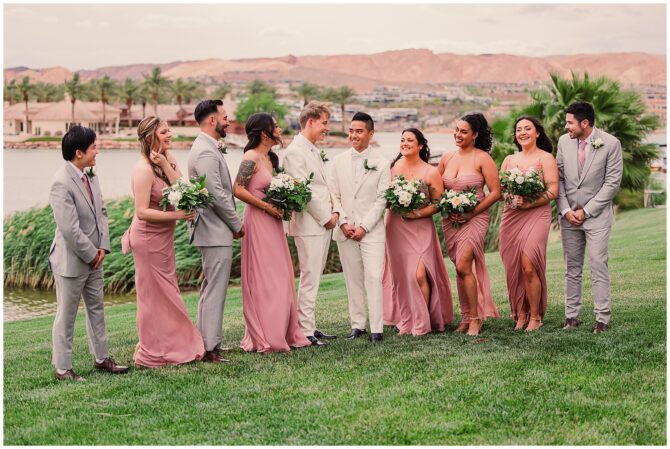Wedding party posing outdoors by a lake.