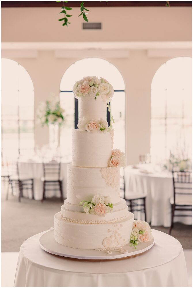 Elegant four-tier wedding cake with floral decorations.