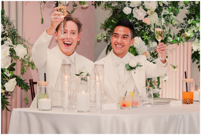 Two grooms toasting at wedding reception.