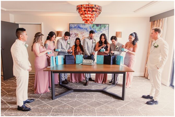 Wedding party opening gift bags together indoors.
