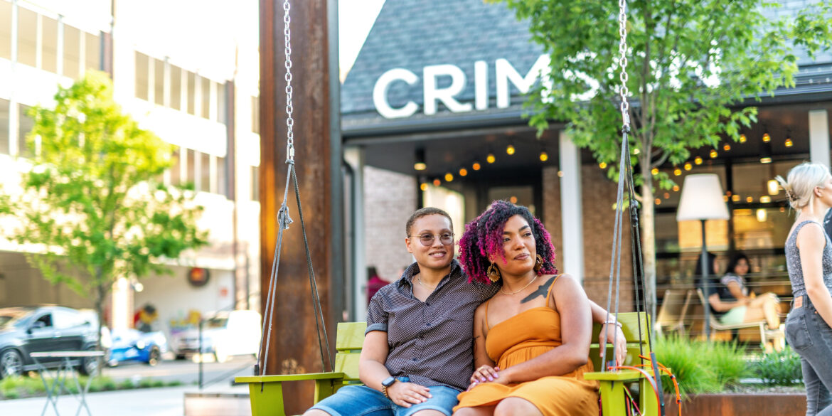 Couple sitting on swing outside cafe.
