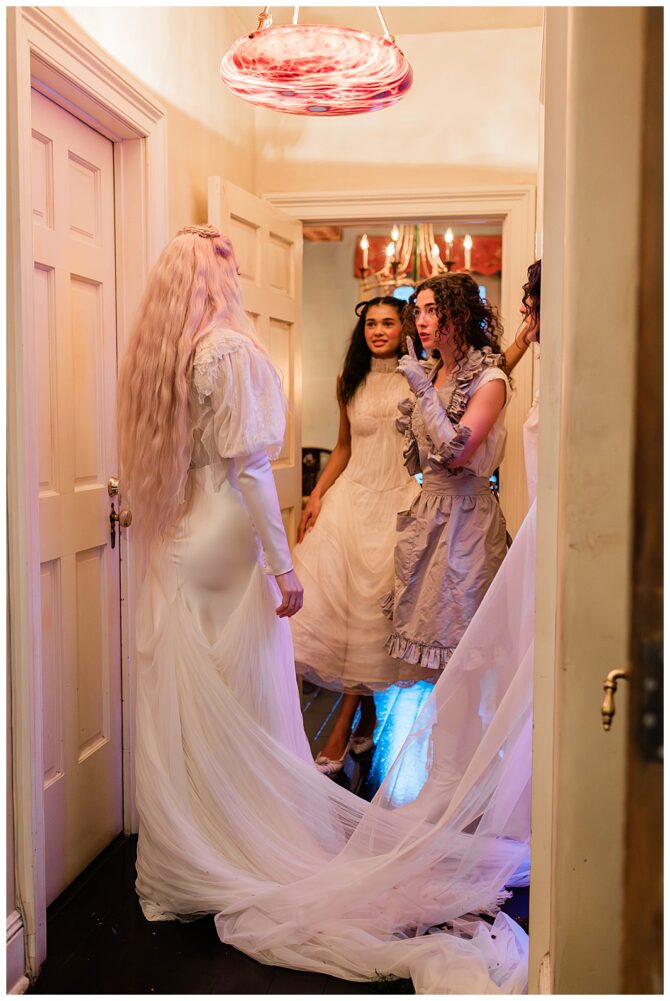People in vintage dresses talking in hallway.