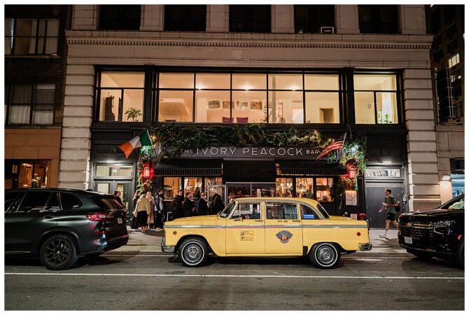 Yellow taxi outside Ivory Peacock Bar at night