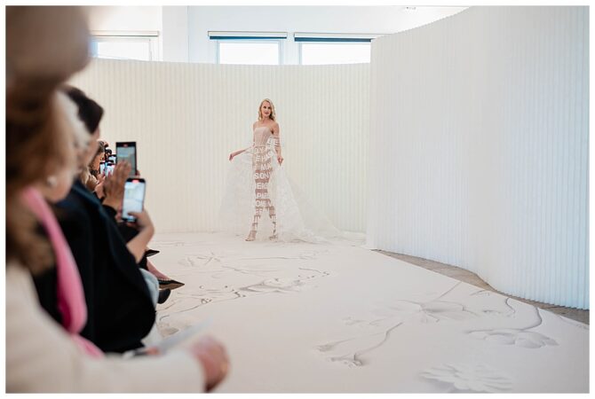 Model walking white textured runway in designer dress.