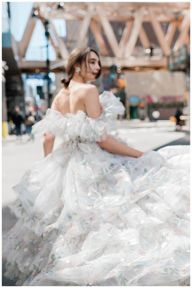 Woman in floral dress on city street.