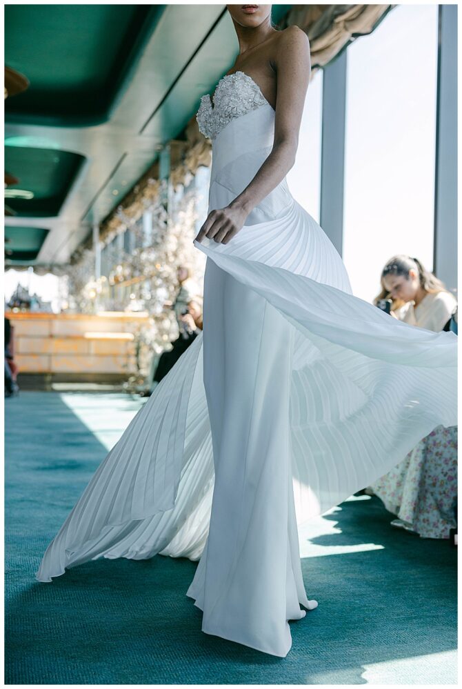 Model in elegant white wedding gown on runway.