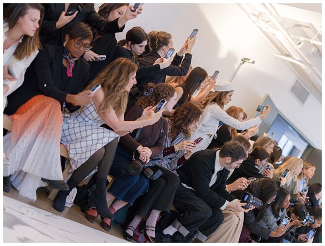 Audience capturing fashion show with smartphones.
