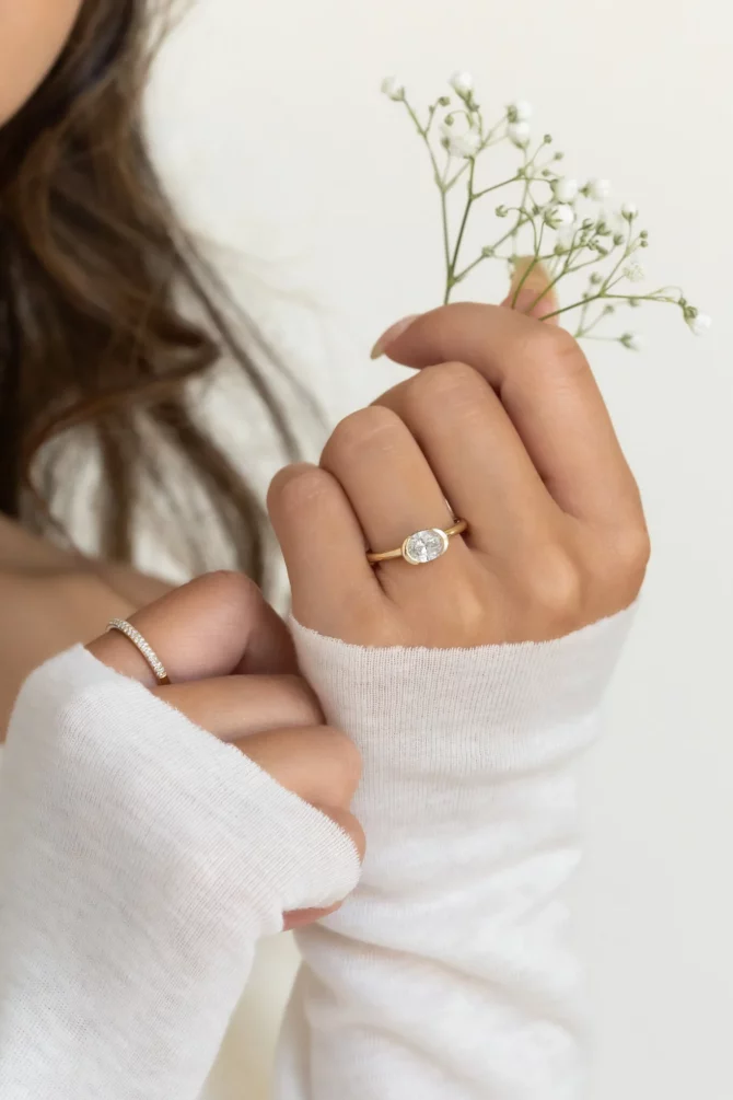 Hand with rings holding delicate flowers.